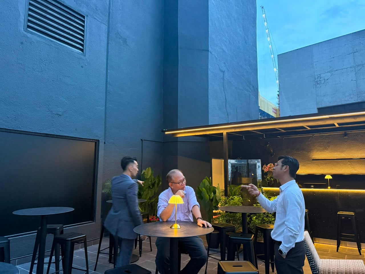 The terrace at blue hour — the bar at the back, garden between tables.