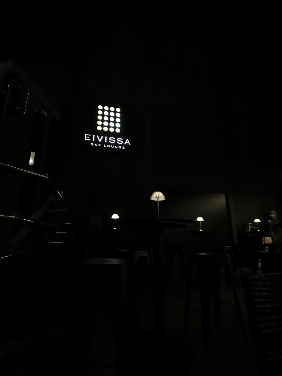 The Eivissa Sky Lounge sign glowing above the terrace, table lamps lit below